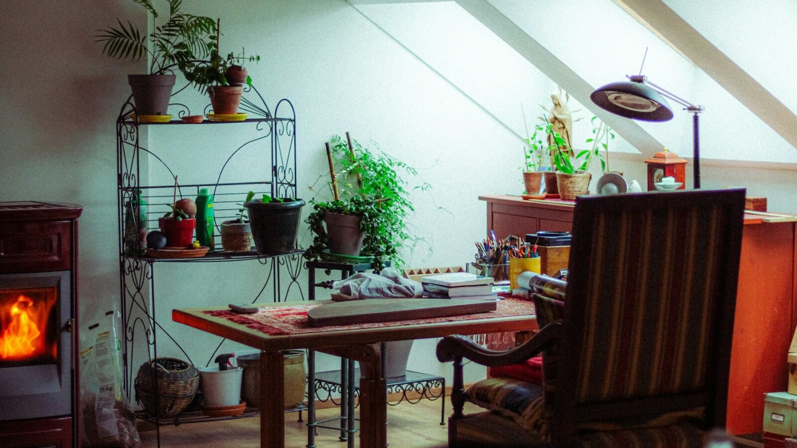 A home office corner with a wooden desk, houseplants and a fireplace